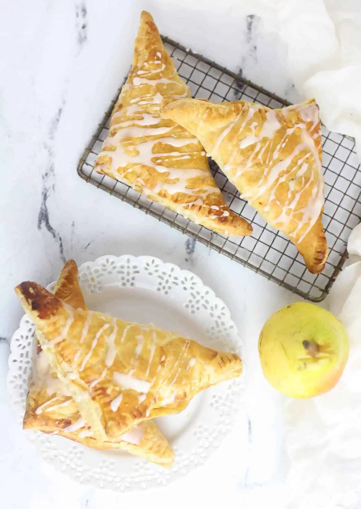 four pear turnovers, two on a plate and two on a cooling rack