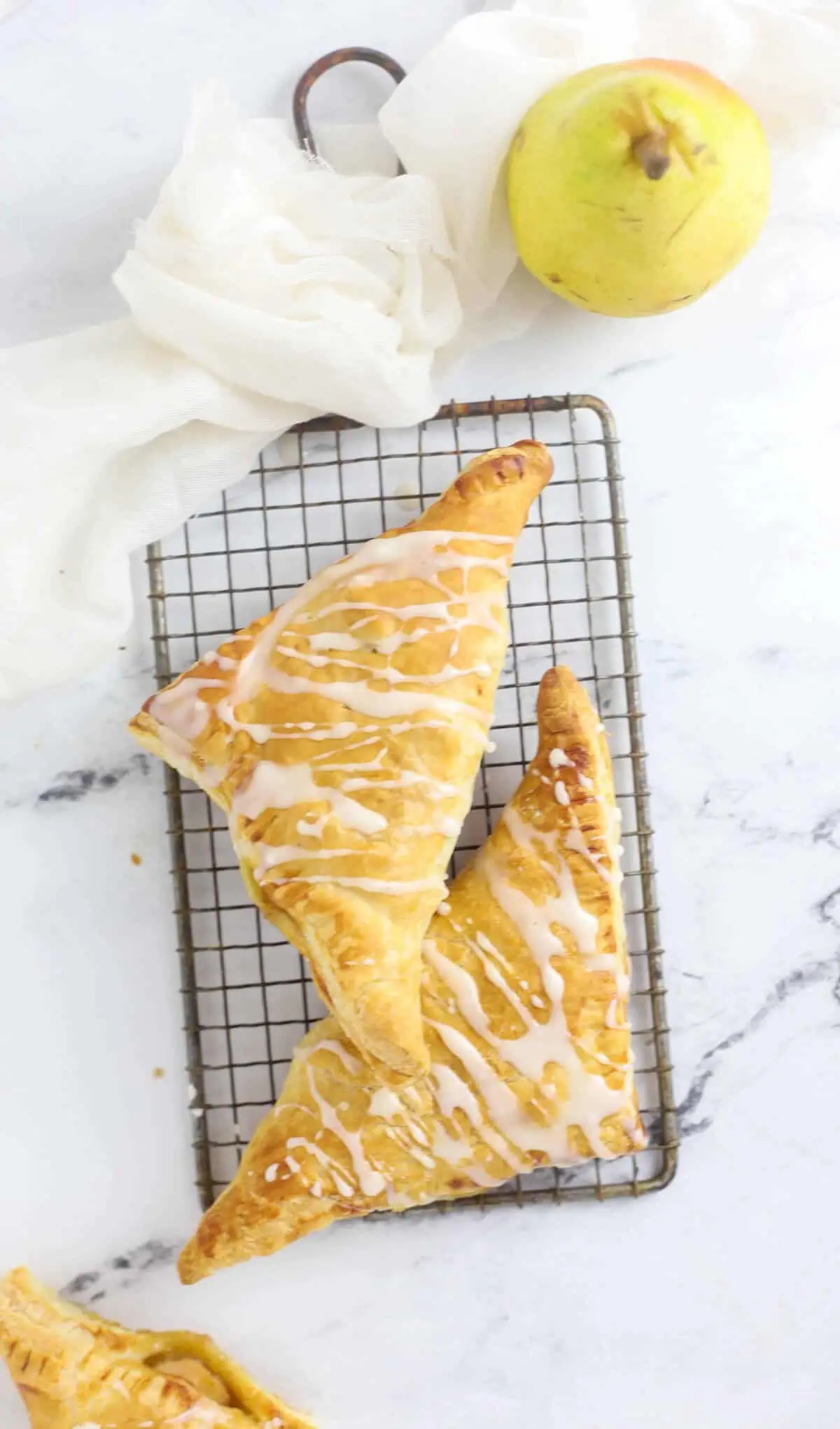 two pear turnovers on a metal cooling rack