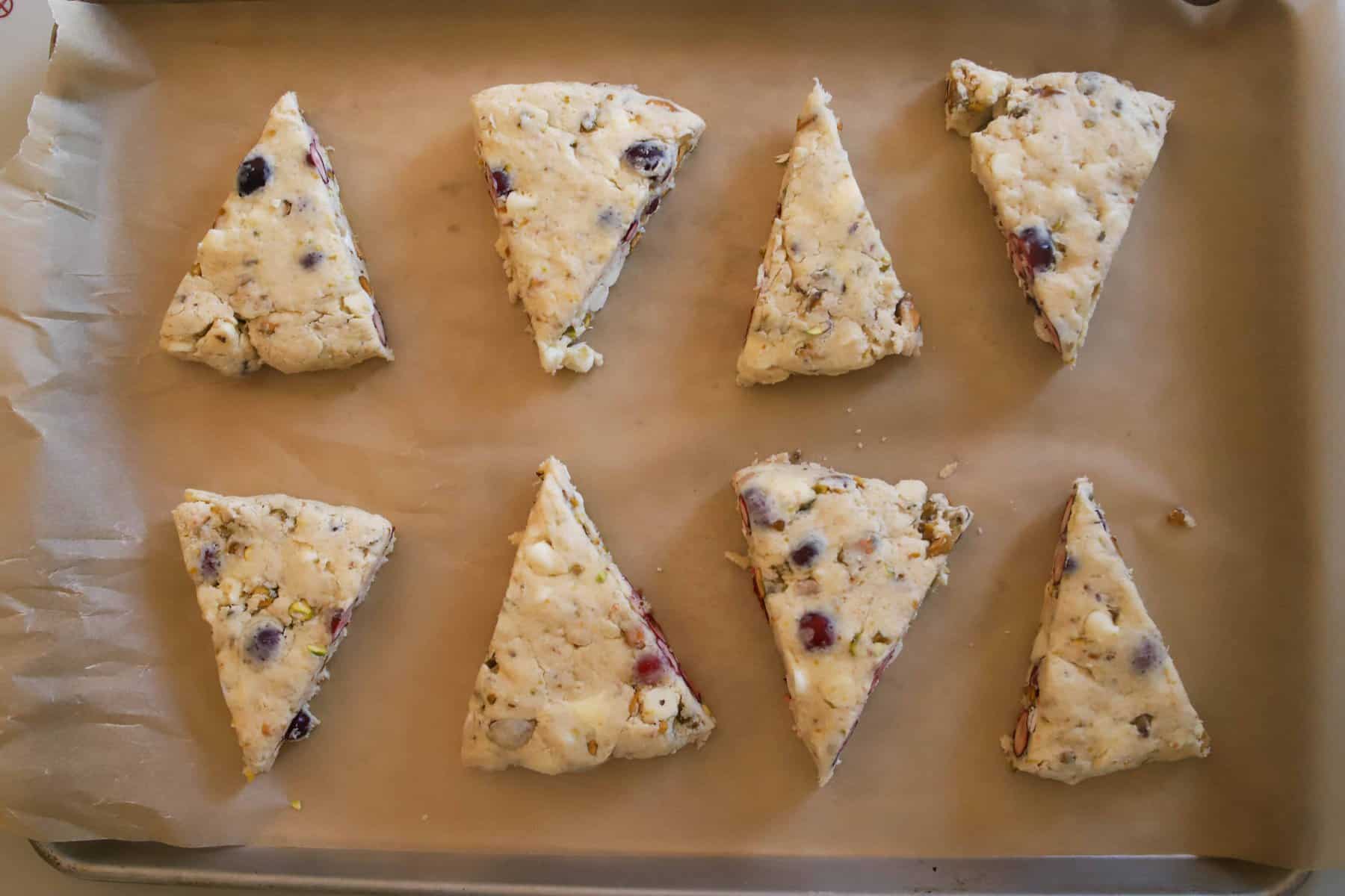 eight unbaked pistachio scones on a baking sheet