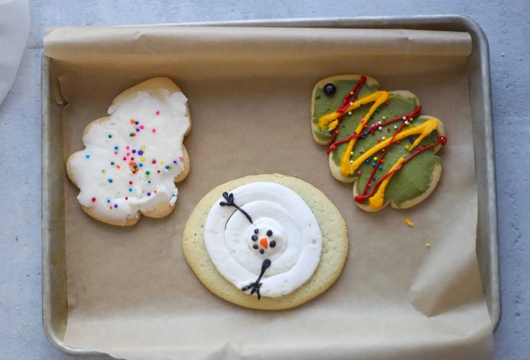 three decorated sugar cookies on a baking sheet