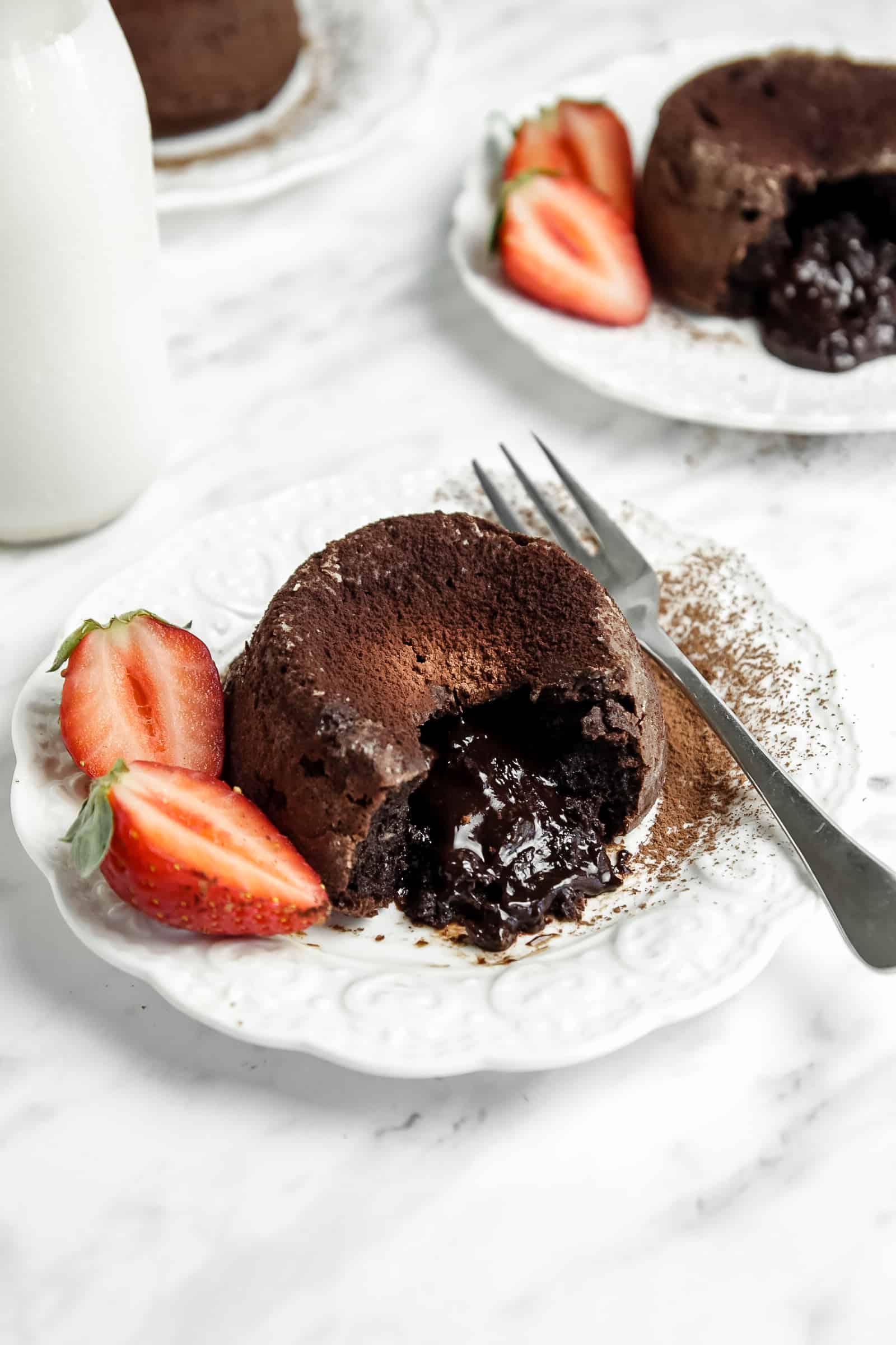 chocolate lava cake on a plate with a fork and strawberries