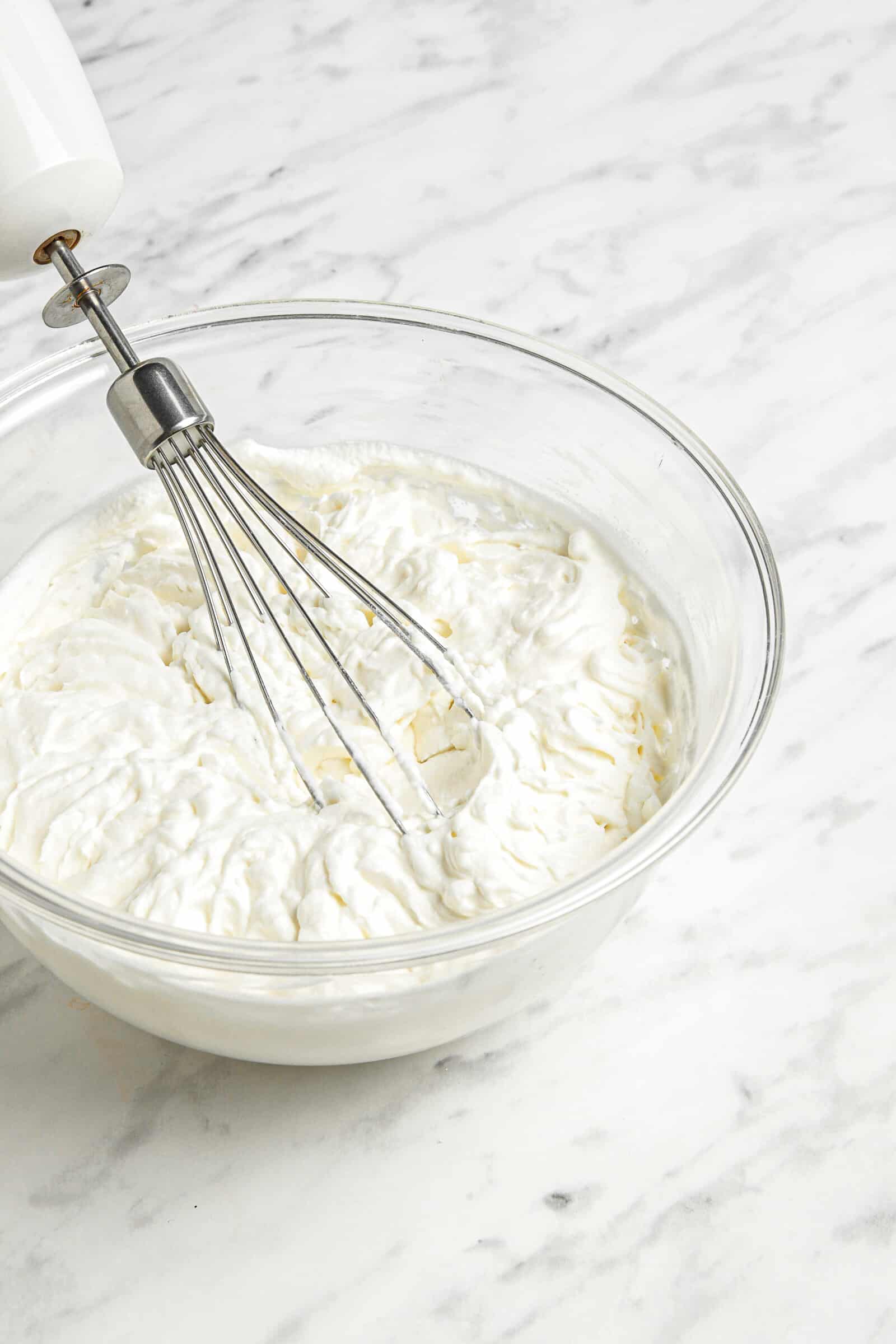 whipped cream in a bowl with an electric whisk