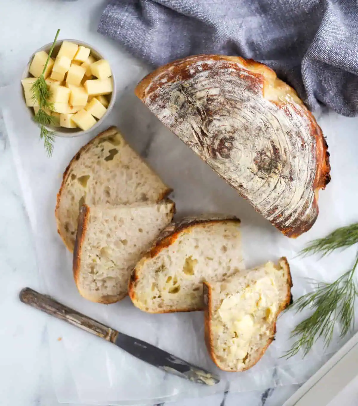 sourdough cheddar loaf with slices cut and a dish of cubed cheddar