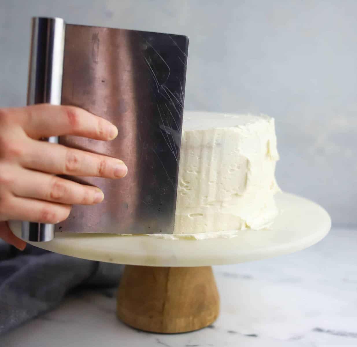 pastry scraper smoothing the sides of a cake