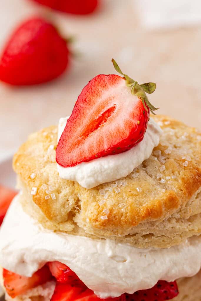 close up of the top of the biscuit topped with whipped cream and half of a strawberry