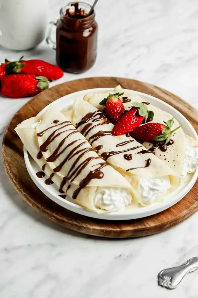 three sourdough crepes on a plate filled with whipped crema
