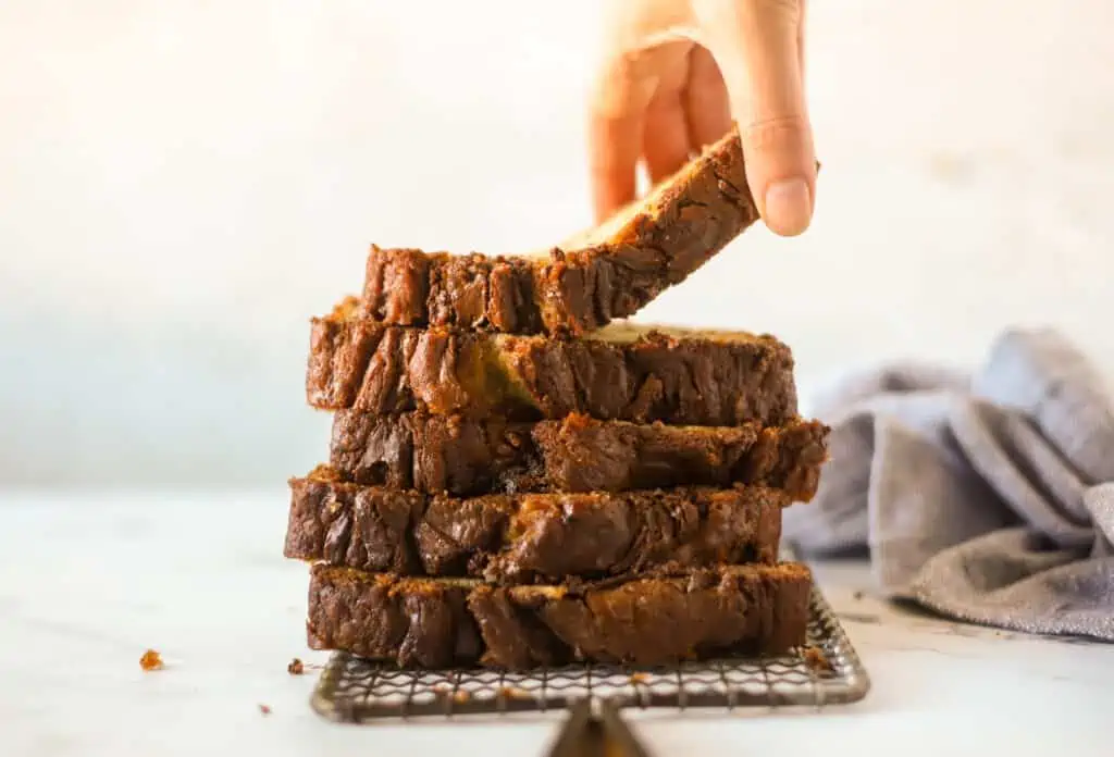hand reaching for a slice of banana nutella bread on a stack of slices