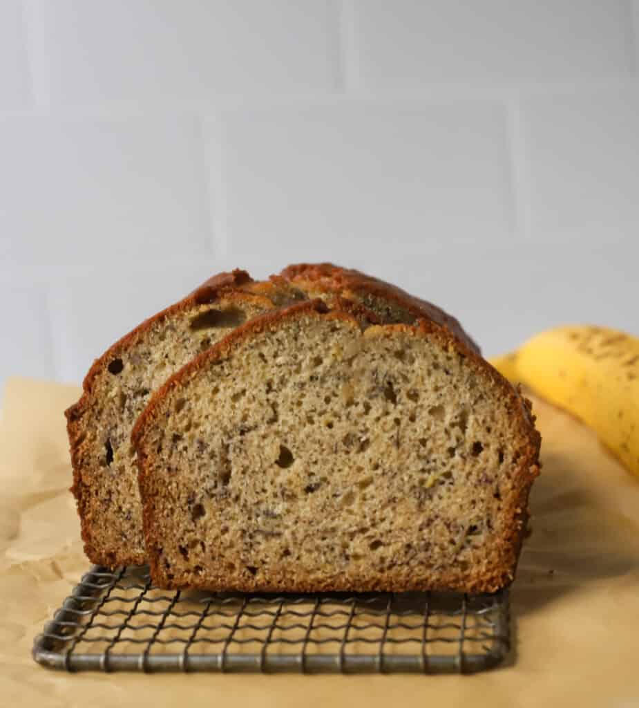 a loaf of sour cream banana bread sliced on a wire rack