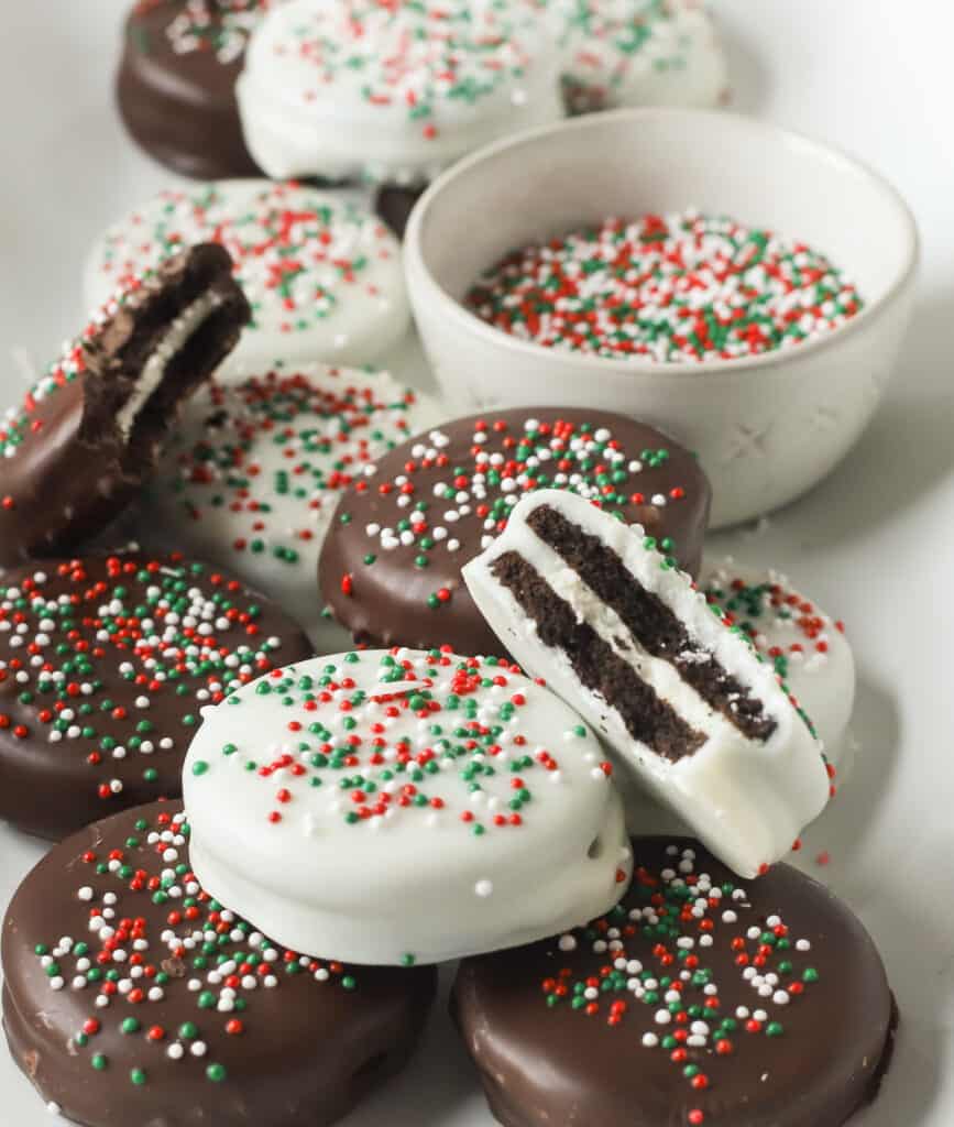 chocolate covered oreos on a plate, one has a bite taken out of it