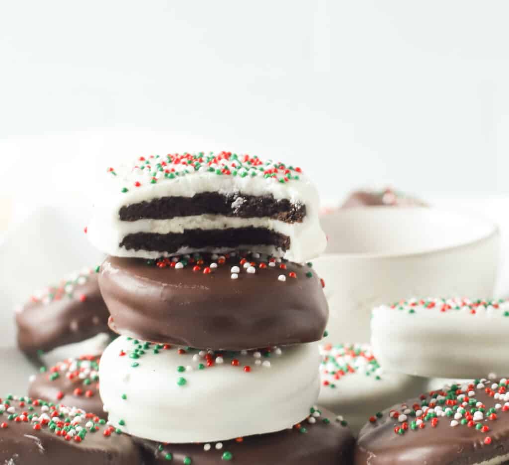 three chocolate covered Oreos stacked on top of each other, the top one has a bite taken out of it