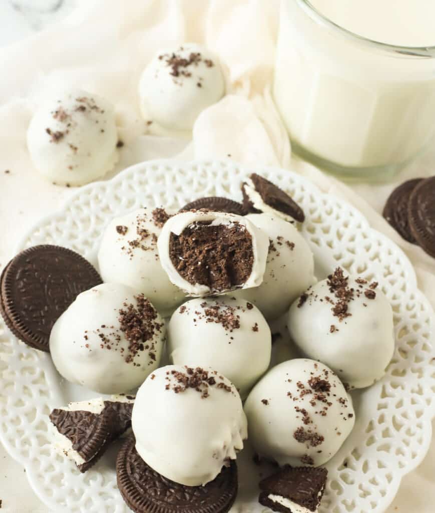 oreo cake balls on a white plate, one has a bite taken out of it