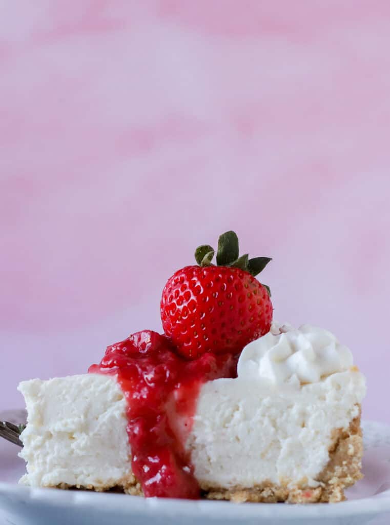 slice of no bake cheesecake with strawberry topping on top and a strawberry