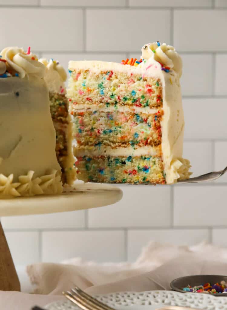 slice of homemade funfetti cake being removed from the cake by a cake server