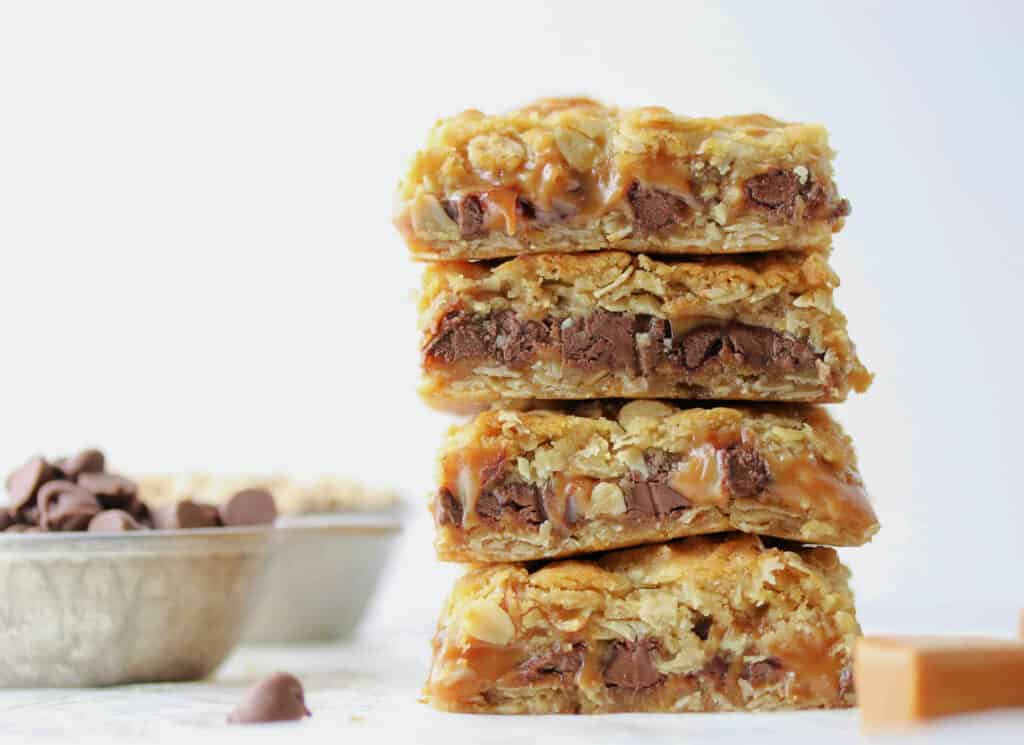 four chocolate caramel oatmeal bars stacked on top of each other