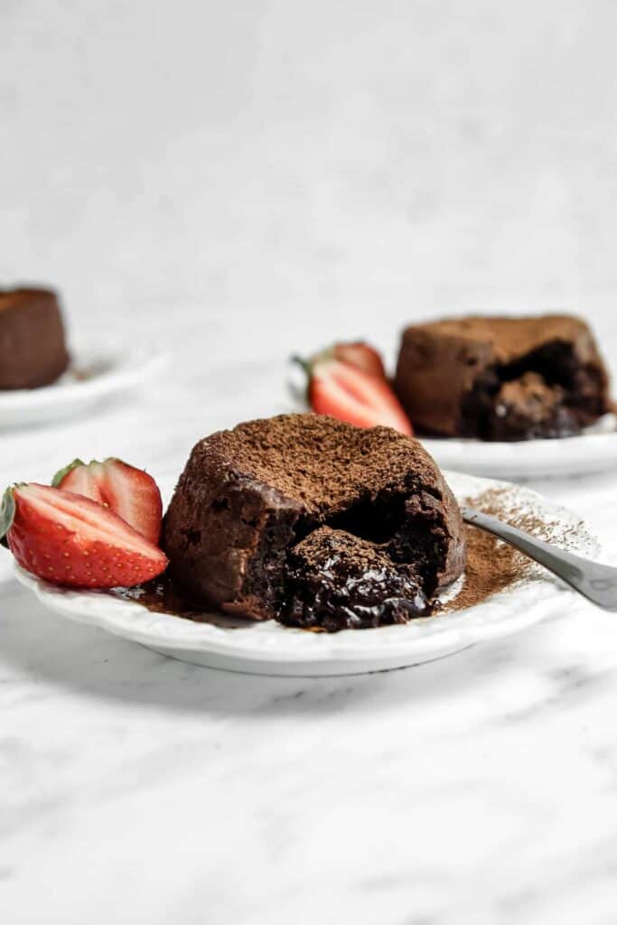 chocolate lava cake on a plate with a fork and strawberries