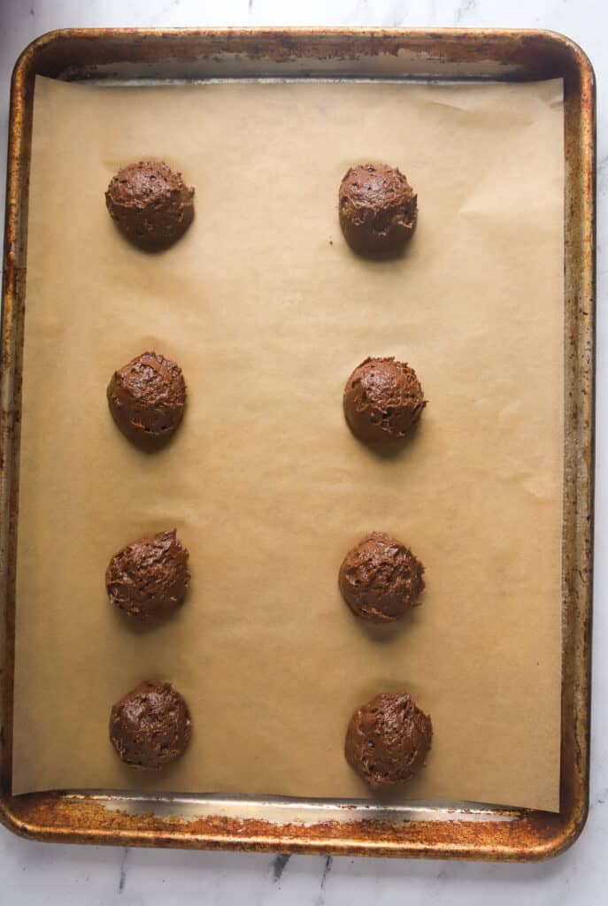 unbaked chocolate whoopie pies on a parchment lined baking sheet