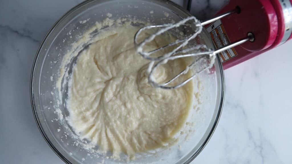 pink electric mixer whipping white cake batter