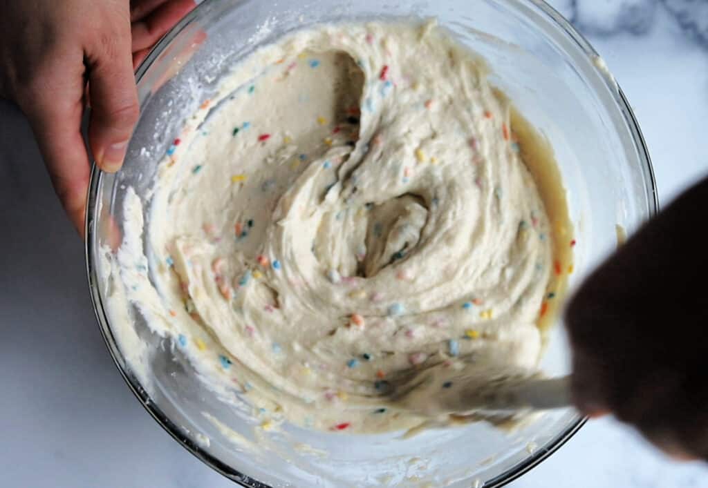sprinkles being stirred into funfetti cake batter