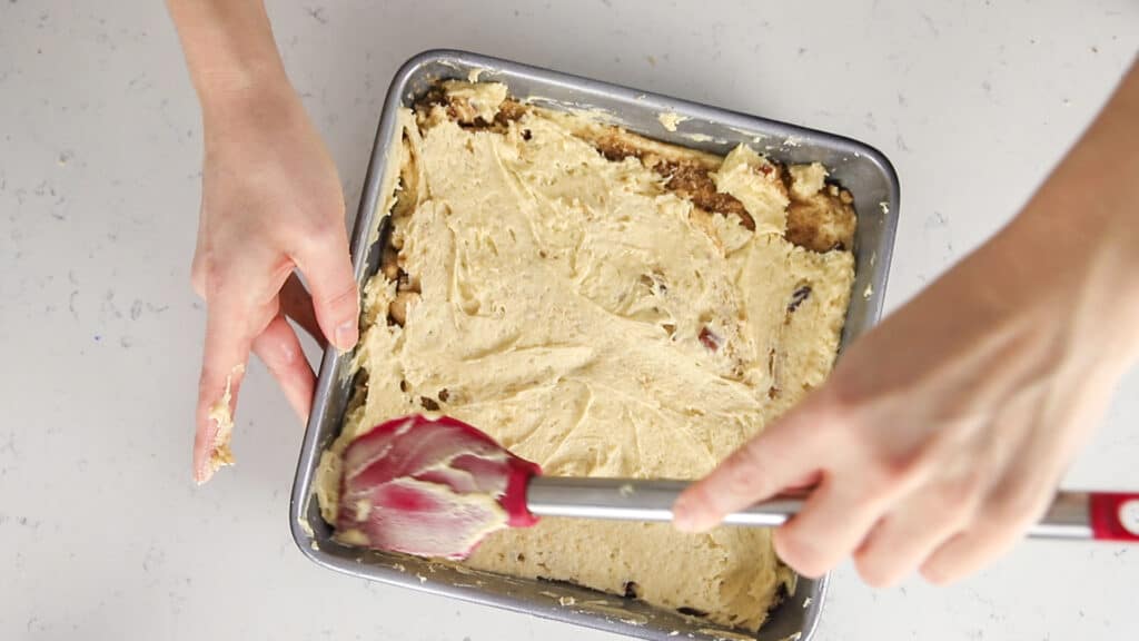 spreading the remaining coffee cake batter on top of streusel layer with a red spatula