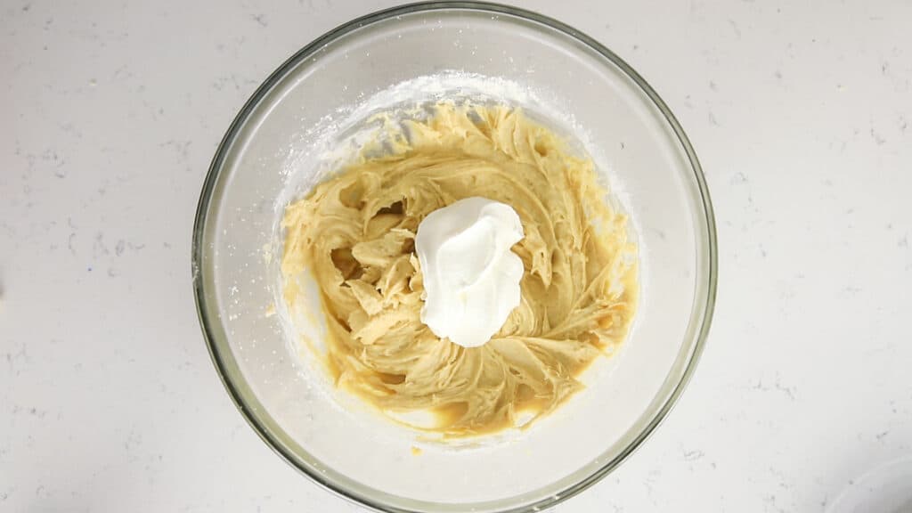 sour cream added to coffee cake batter in glass bowl