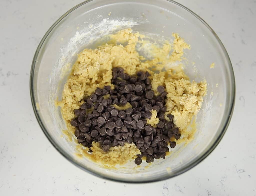cookie dough with chocolate chips poured on top in a glass bowl