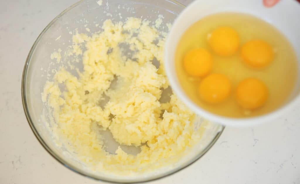 5 eggs in a bowl and a bowl of beaten butter