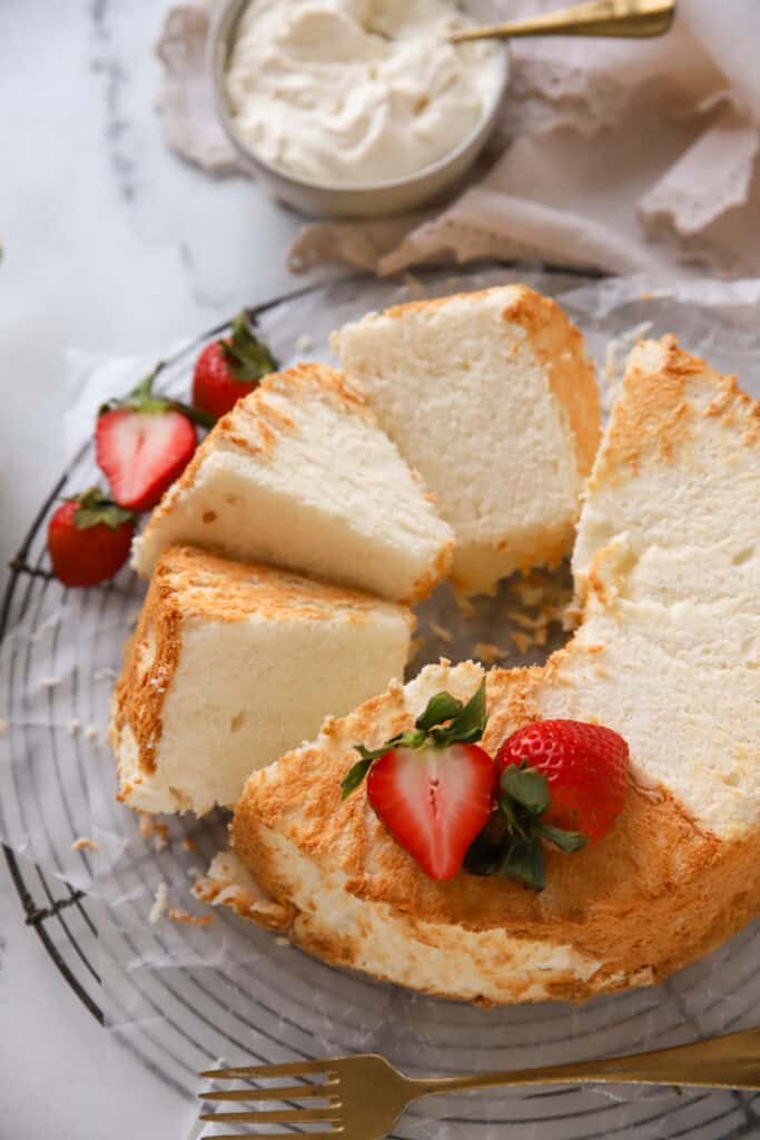 angel food cake sliced on a cooling rack topped with strawberries