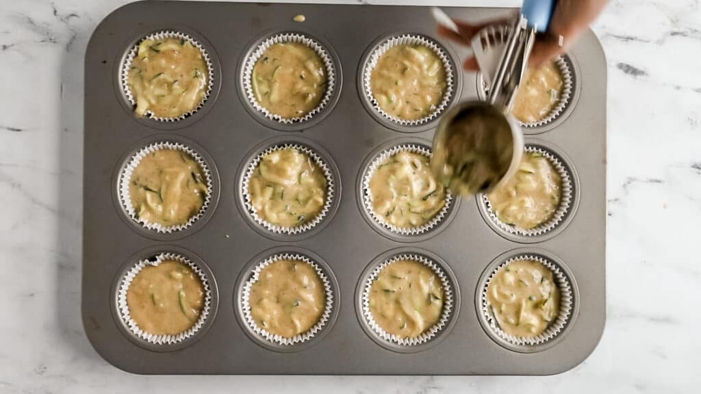 muffin scoop scooping zucchini bread muffin batter into muffin liners in apn