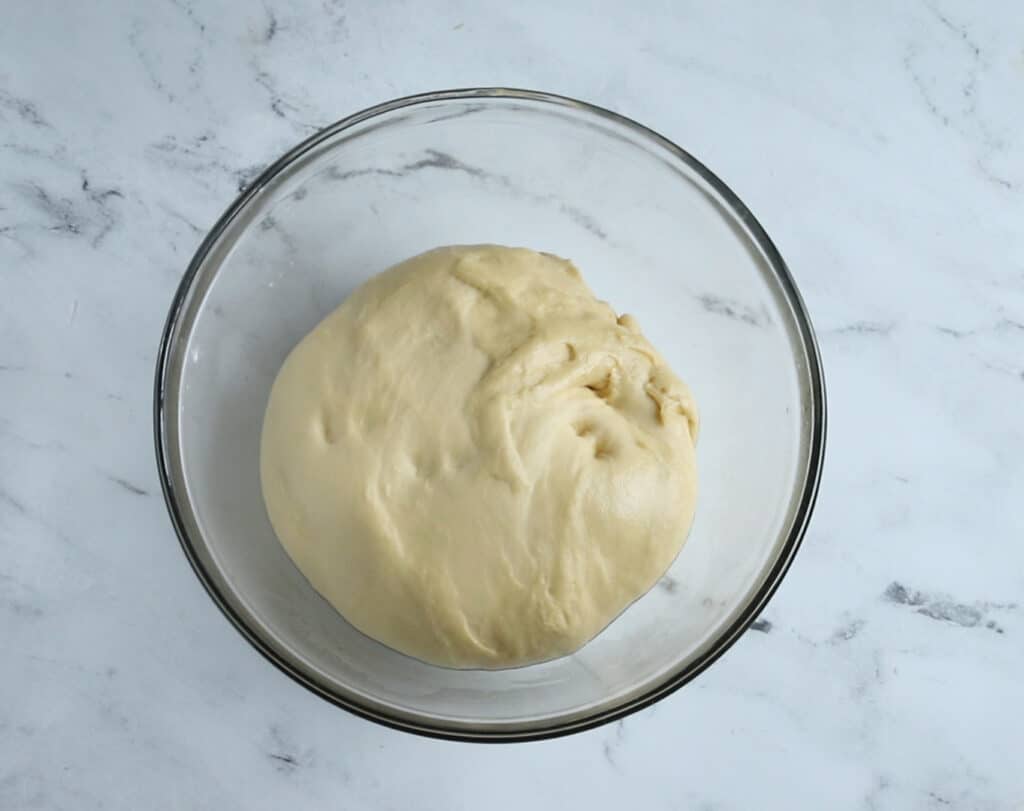 risen cinnamon roll dough in a glass bowl