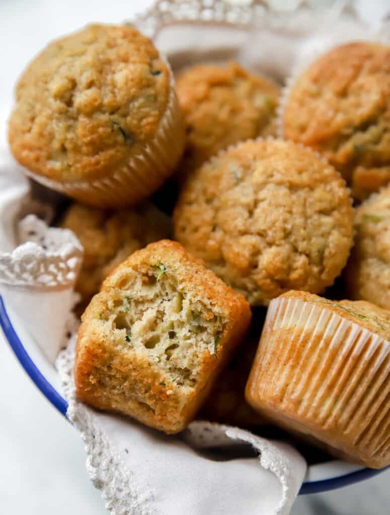 zucchini bread muffins in a basket lined with a napkin