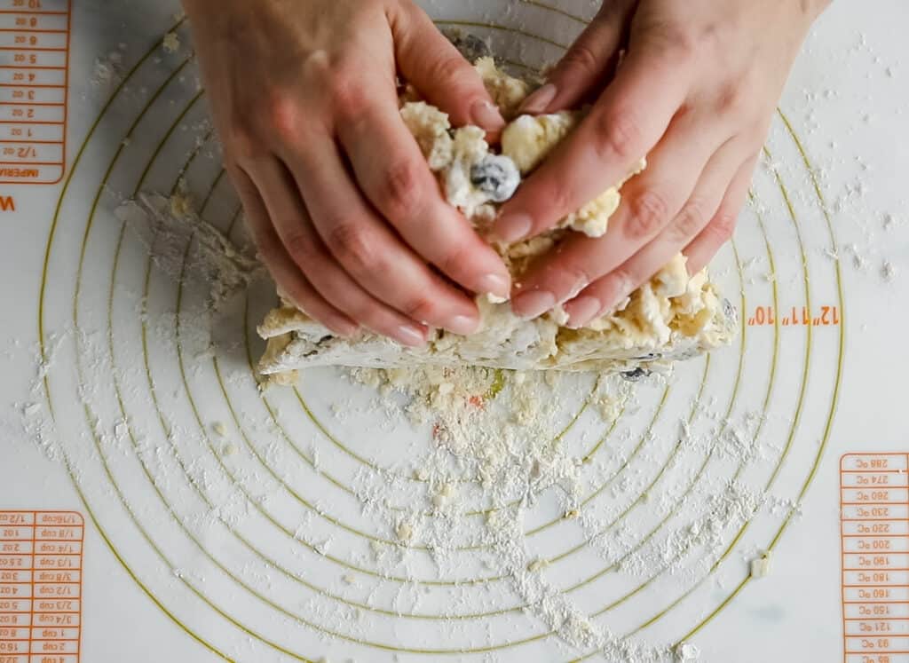 hand pressing scone dough together on a pastry mat