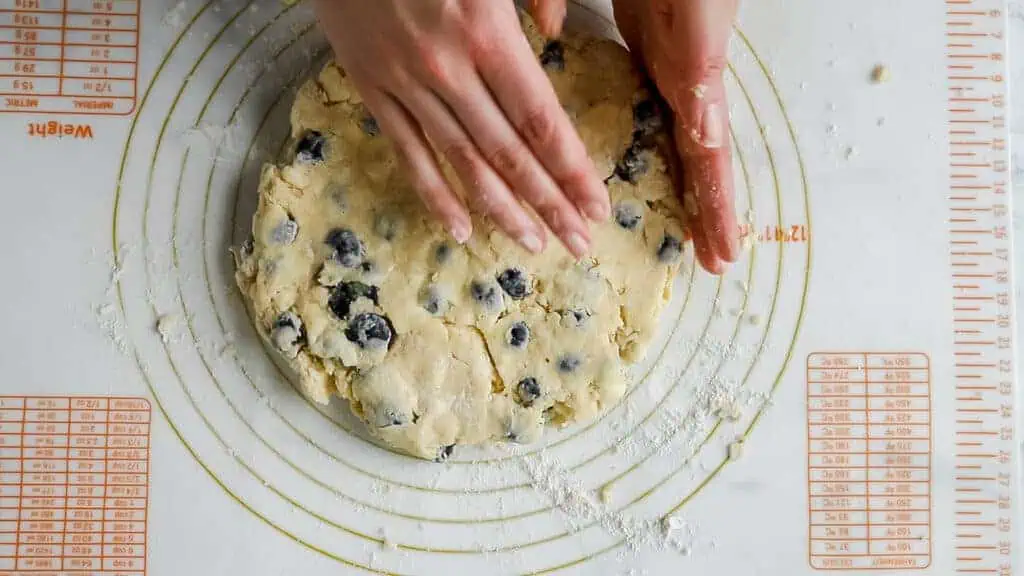hand pressing scone dough into an 8" circle