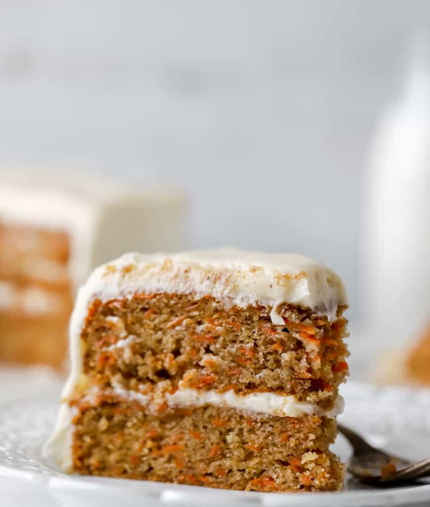 slice of carrot layer cake upright on a white plate