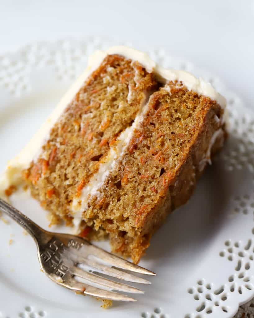 slice of carrot cake on a white plate with a fork