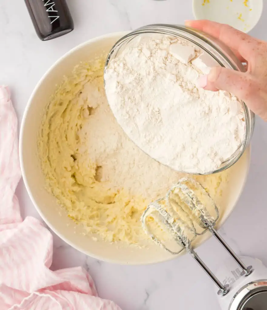 flour being added to cupcake batter in bowl