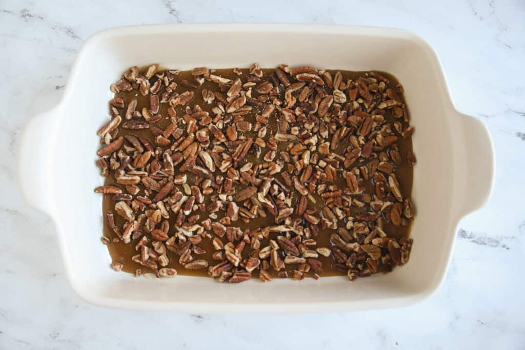 pecans sprinkled over pecan sticky bun topping in 9x13 pan