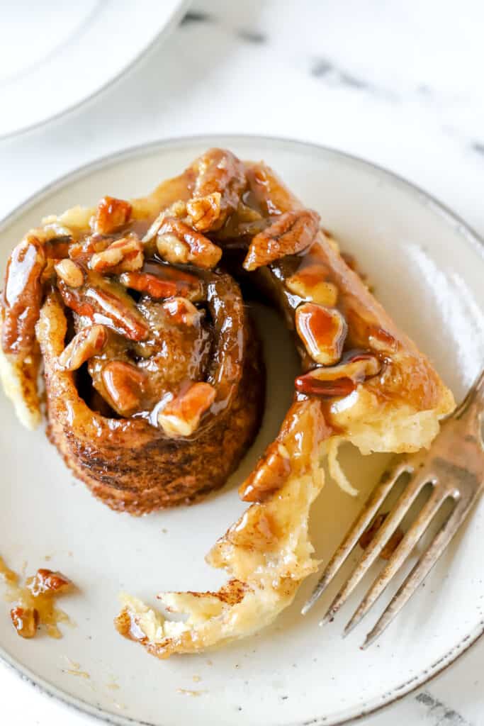 unraveled pecan sticky bun on a plate with a fork