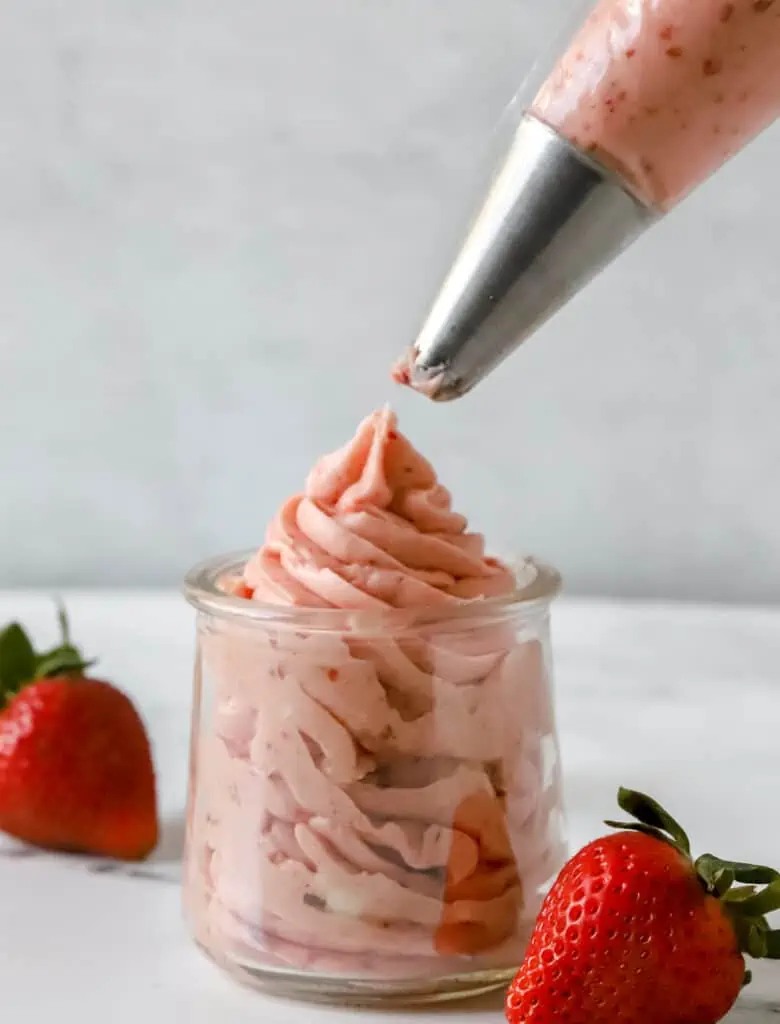 piping bag piping strawberry cream cheese frosting into weck jar