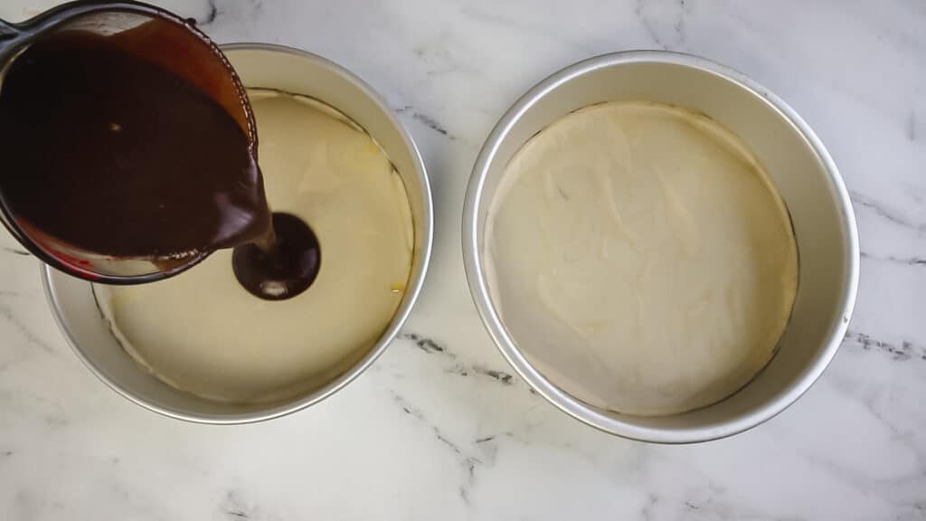 chocolate cake batter being poured into cake pans