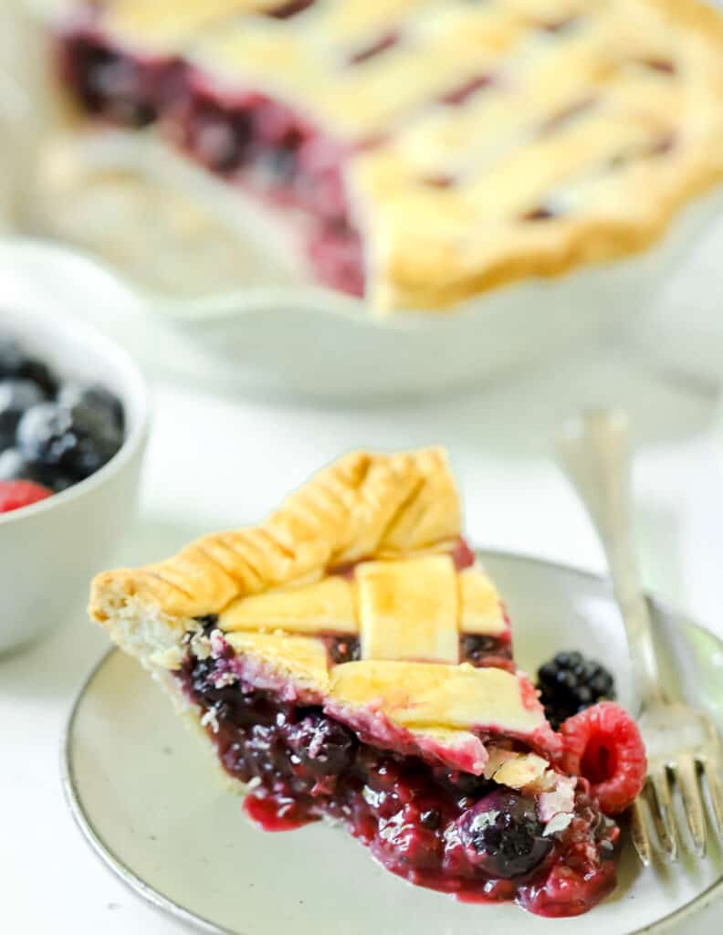 slice of triple berry pie on a plate with a fork