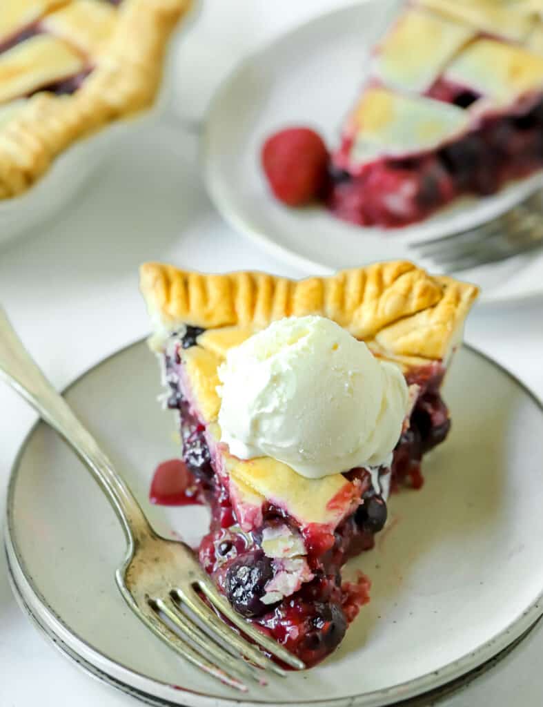 slice of triple berry pie topped with a scoop of vanilla ice cream