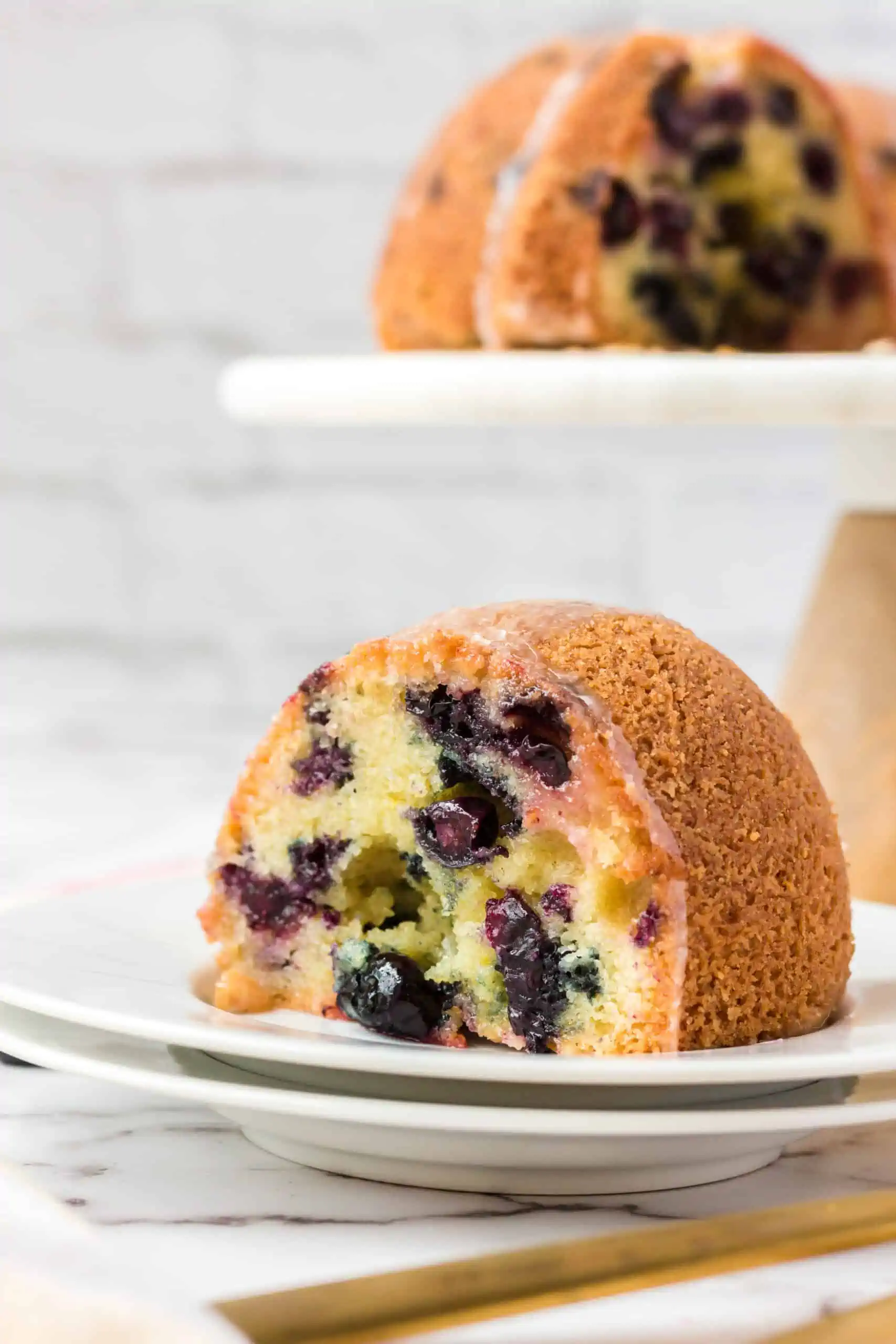 blueberry pound cake slice on a plate with bundt cake in background