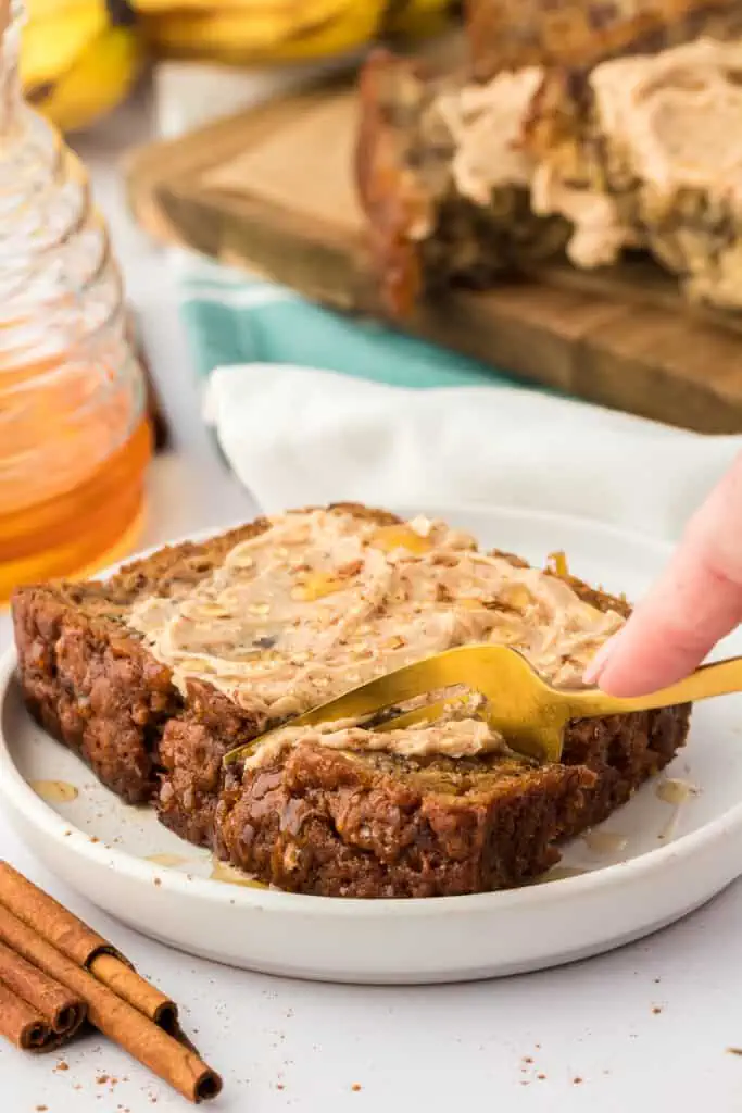 person eating a slice of banana bread topped with cinnamon butter