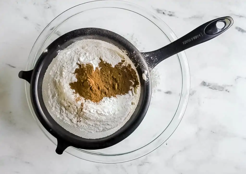 pumpkin cake dry ingredients in a sifter over a bowl