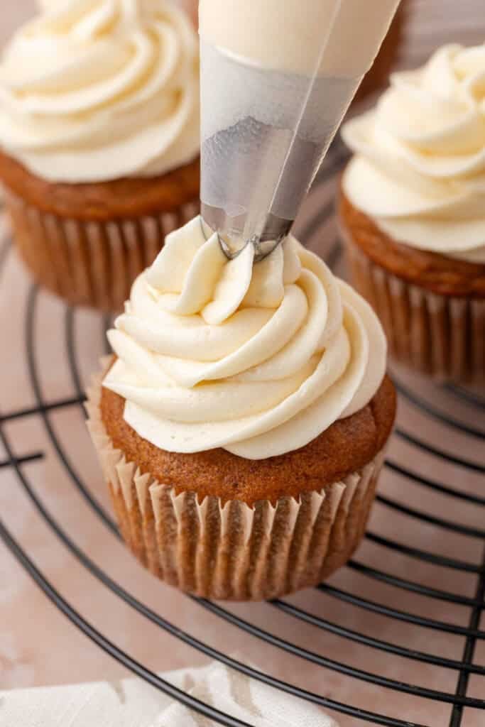cream cheese frosting piped onto a pumpkin cupcake
