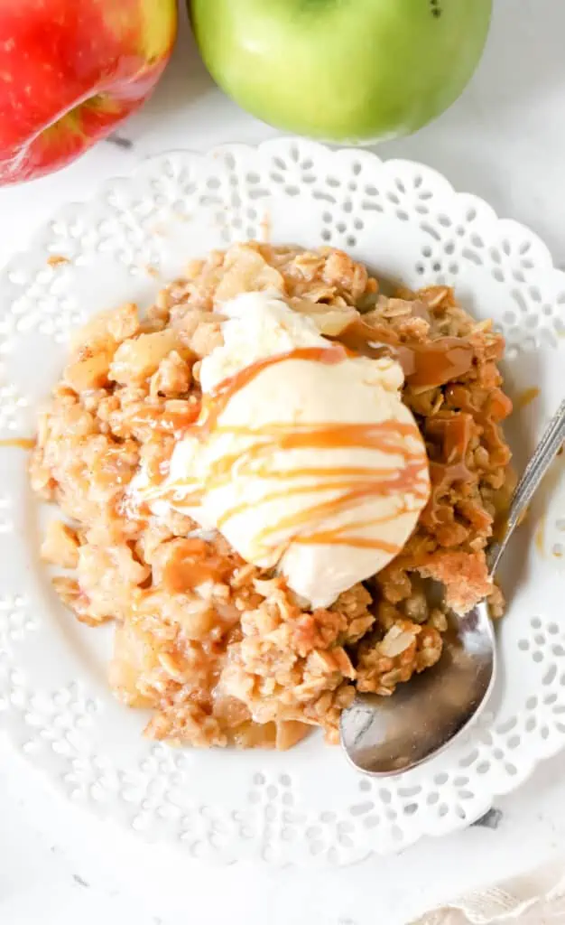 top down view of apple crisp on a plate topped with ice cream and caramel