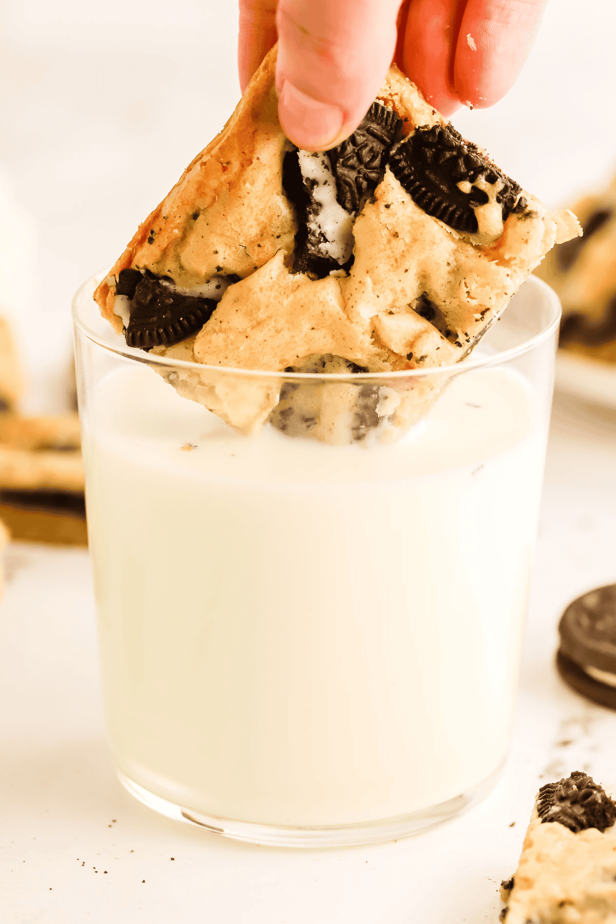 Oreo blondie being dunked into a glass of milk