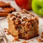 slice of apple crumb cake on a plate with a bite missing