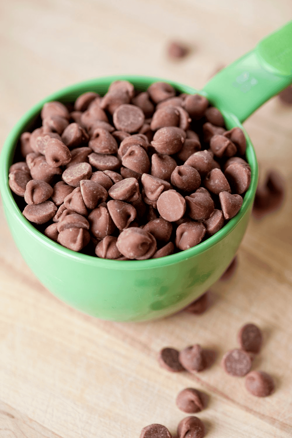 green measuring cup filled with chocolate chips