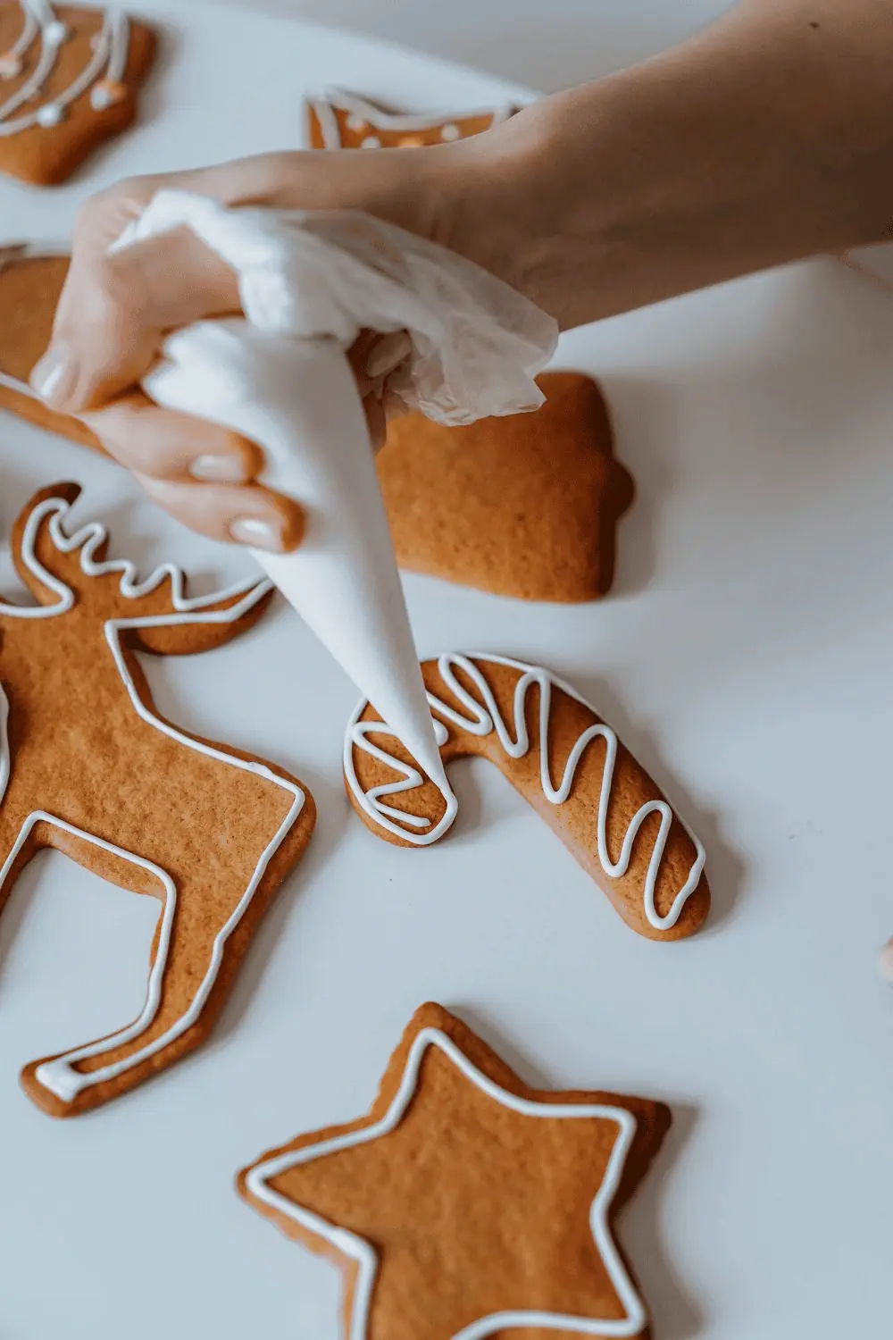 gingerbread cookie being decorated with white cookie glaze